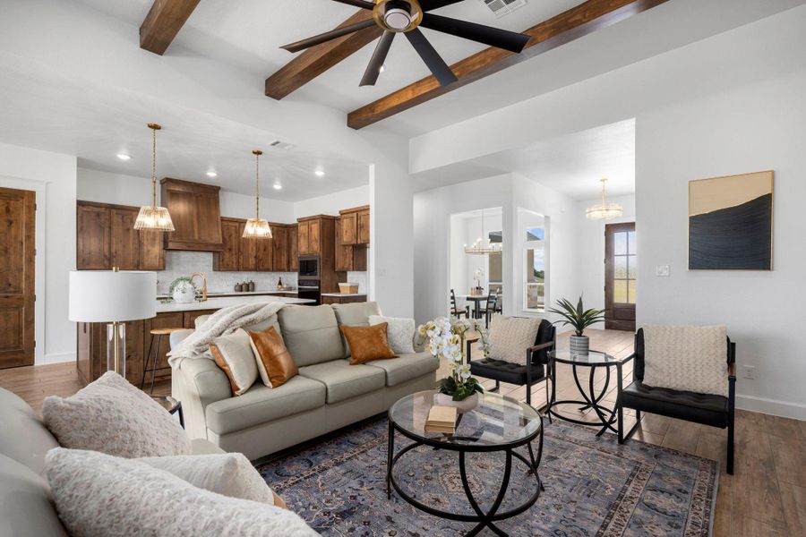 Living room with beamed ceiling, dark wood finished floors, ceiling fan, and a chandelier