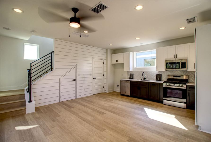 Kitchen featuring white cabinetry, stainless steel appliances, light countertops, a ceiling fan, and light wood-style floors Kitchen featuring white cabinetry, stainless steel appliances, light countertops, a ceiling fan, and light wood-style floors