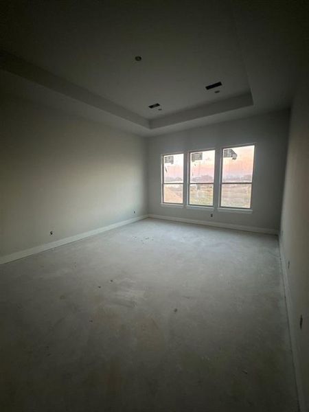 Spare room featuring a tray ceiling and unfinished concrete flooring