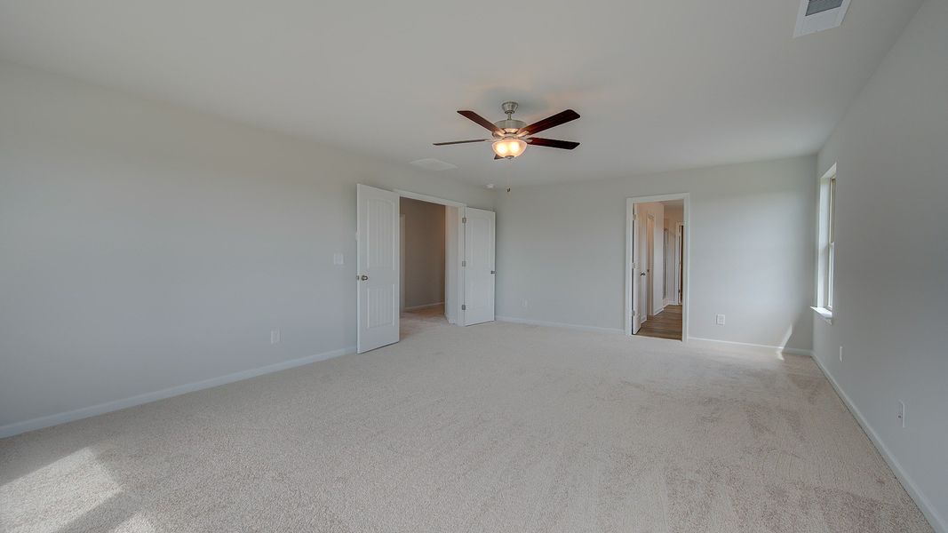Stonefield double-door entry primary suite with tray ceiling, carpet flooring, and spacious layout at Brighton.