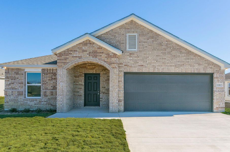 View of front of home featuring brick siding, a front yard, and a garage