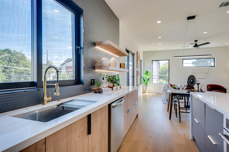 Kitchen with sink, dishwasher, backsplash, light hardwood / wood-style floors, and pendant lighting