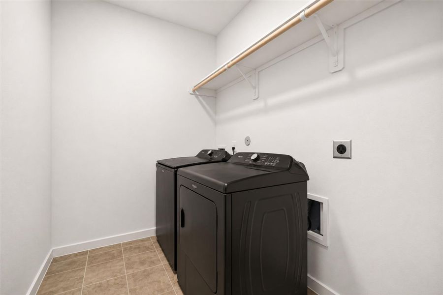 Dedicated laundry room featuring upper storage shelving, tile flooring, and functional space for everyday convenience and organization. Clean layout with room for additional storage solutions if desired.