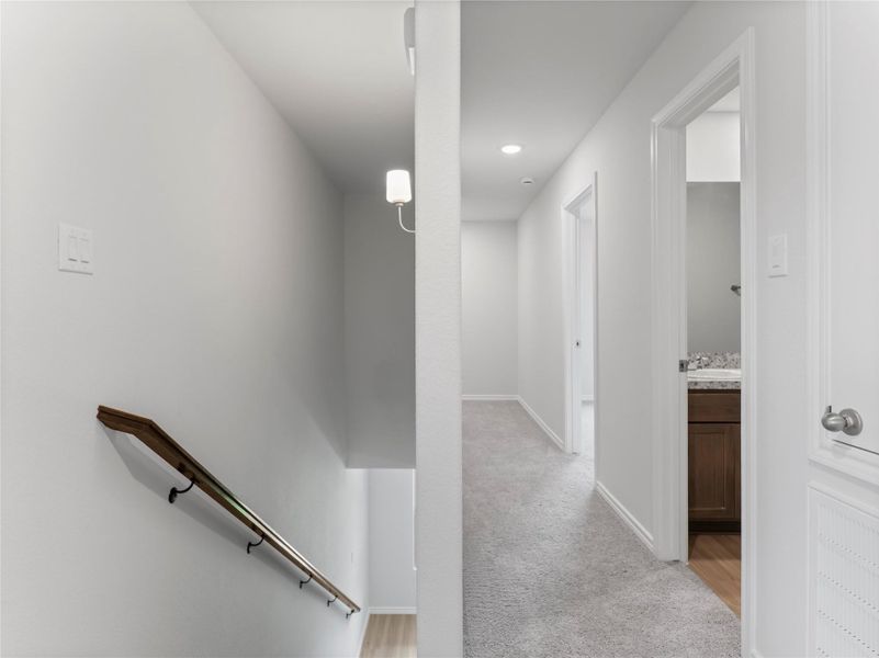 Cozy carpeted upstairs hallway leading to spacious rooms and a bathroom. Cozy carpeted upstairs hallway leading to spacious rooms and a bathroom.