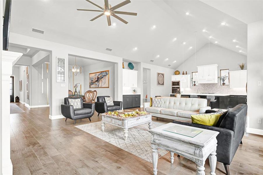 Living area with high vaulted ceiling, a ceiling fan, light wood-type flooring, and recessed lighting