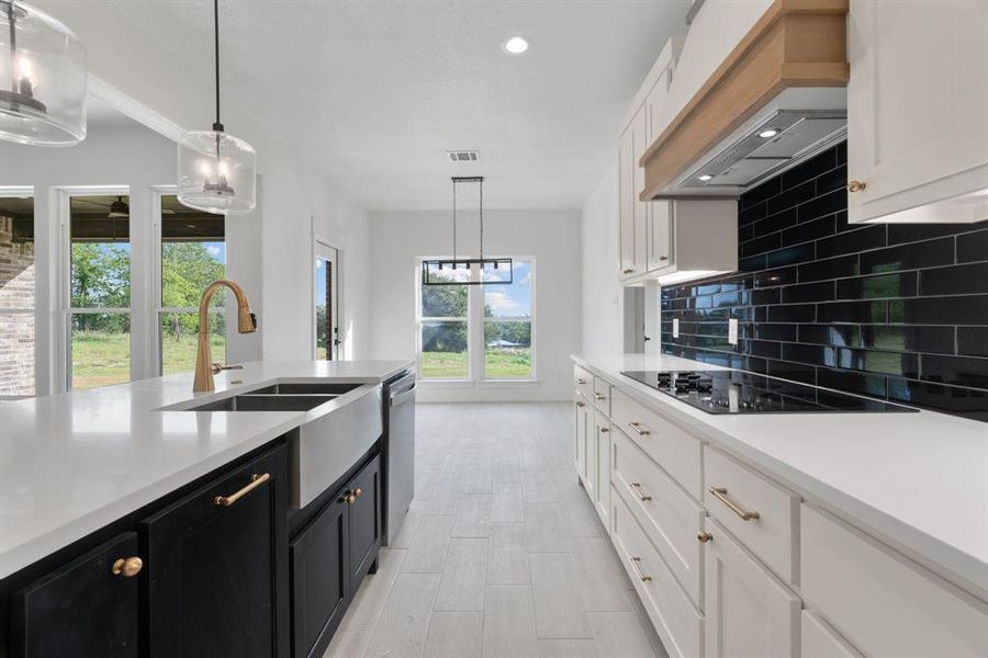 Kitchen with stainless steel dishwasher, a center island with sink, light countertops, white cabinets, and a ceiling fan