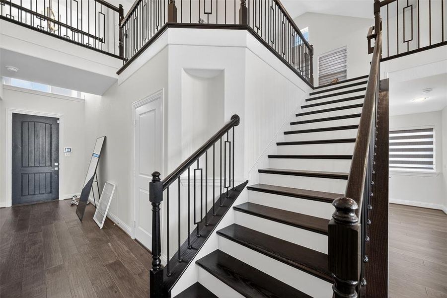 Foyer entrance with a towering ceiling, dark wood-type flooring, and stairs Foyer entrance with a towering ceiling, dark wood-type flooring, and stairs