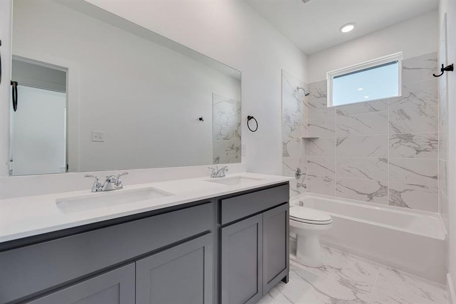Bathroom with bathing tub / shower combination, double vanity, and light marble finish floors Bathroom with bathing tub / shower combination, double vanity, and light marble finish floors