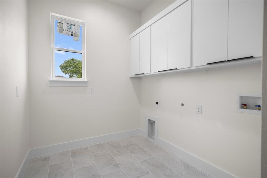 Utility room featuring tiled flooring, a window providing natural light, and white cabinetry with dark handles Utility room featuring tiled flooring, a window providing natural light, and white cabinetry with dark handles