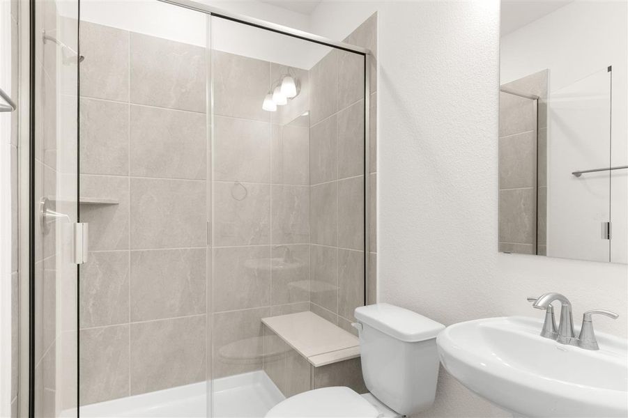 Bathroom featuring a sink, toilet, and a stall shower