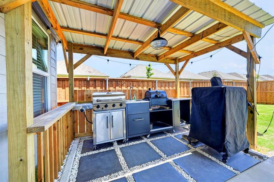 Covered patio with exposed wood beams and a corrugated metal roof