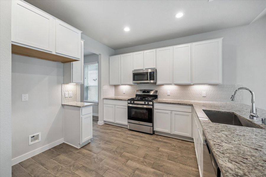 This modern kitchen features sleek stone countertops, white cabinetry, and stainless steel appliances. It has a spacious layout with ample storage, a large sink, and a stylish backsplash, perfect for cooking and entertaining. This modern kitchen features sleek stone countertops, white cabinetry, and stainless steel appliances. It has a spacious layout with ample storage, a large sink, and a stylish backsplash, perfect for cooking and entertaining.