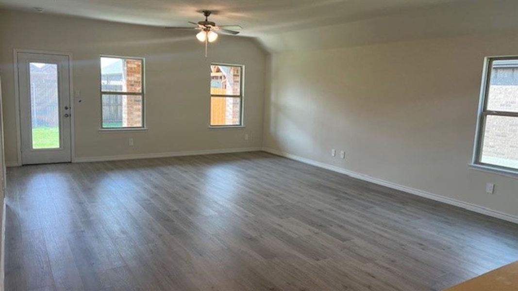 Empty room featuring wood finished floors, vaulted ceiling, and a ceiling fan Empty room featuring wood finished floors, vaulted ceiling, and a ceiling fan