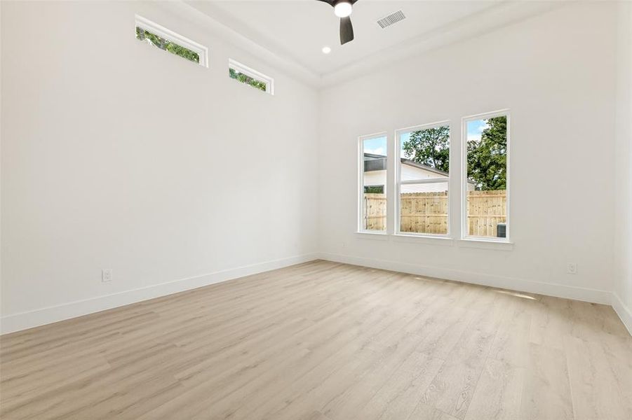 Room featuring light wood-finish flooring, white walls, and a vaulted ceiling Room featuring light wood-finish flooring, white walls, and a vaulted ceiling