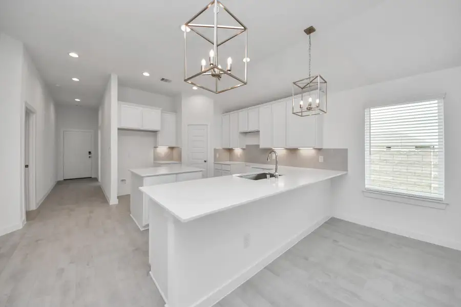 The kitchen is a culinary haven, featuring granite countertops, a tile backsplash, stainless steel appliances, 42” upper cabinets, and undercabinet lighting. Sample photo of completed home with similar floor plan. Actual colors and selections may vary.