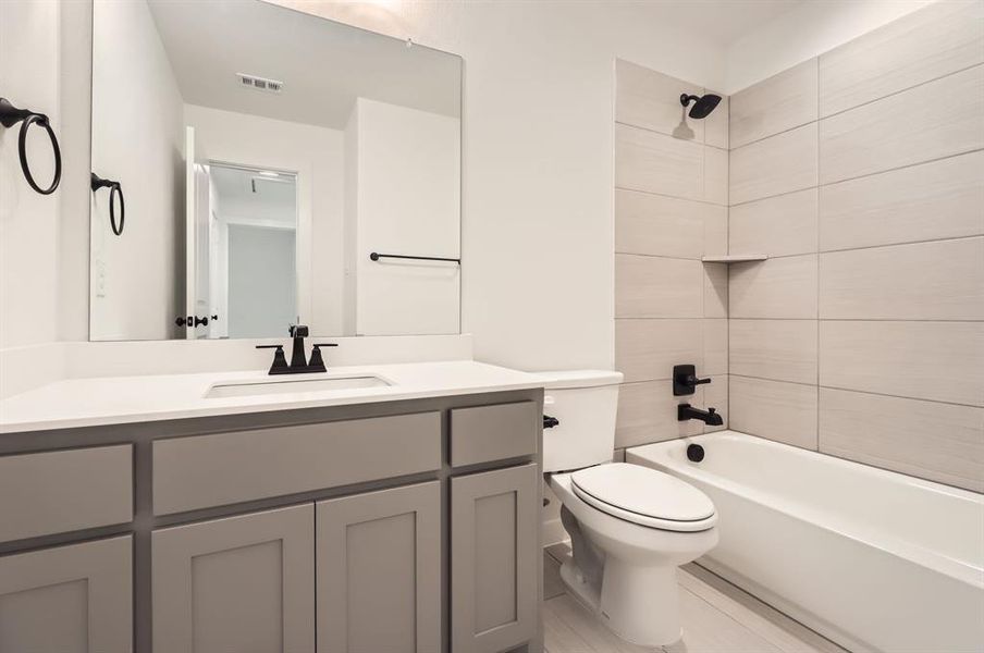 Full bathroom with vanity, tiled shower / bath combo, and toilet