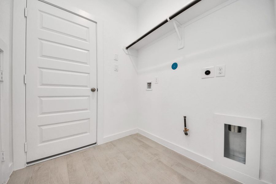 A perfect blend of functionality and comfort. Capture the essence of easy living with a first-floor laundry room, thoughtfully equipped with shelving for effortless organization. Both electric and gas connections available. Sample photo of completed home with similar floor plan. Actual colors and selections may vary.