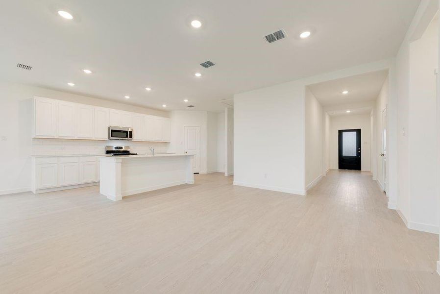 Kitchen featuring open floor plan, an island with sink, recessed lighting, light wood-type flooring, and white cabinetry Kitchen featuring open floor plan, an island with sink, recessed lighting, light wood-type flooring, and white cabinetry