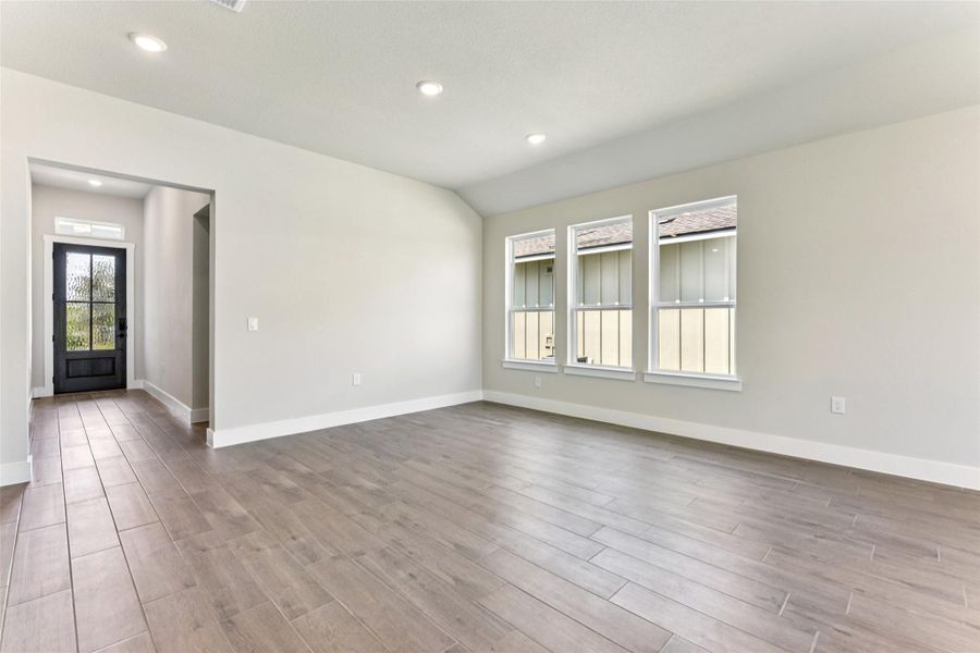 Empty room with light wood-style flooring, recessed lighting, and lofted ceiling Empty room with light wood-style flooring, recessed lighting, and lofted ceiling