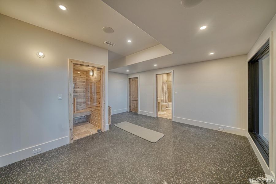 A purpose-designed fitness studio with durable flooring sits just off the family room and includes direct access to the sauna and a full bath, creating a private space for movement, recovery, or personal training. A purpose-designed fitness studio with durable flooring sits just off the family room and includes direct access to the sauna and a full bath, creating a private space for movement, recovery, or personal training.