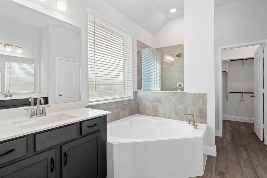 This spa-inspired primary bathroom showcases a sleek soaking tub with a tiled accent wall and window with privacy blinds for natural light. This spa-inspired primary bathroom showcases a sleek soaking tub with a tiled accent wall and window with privacy blinds for natural light.