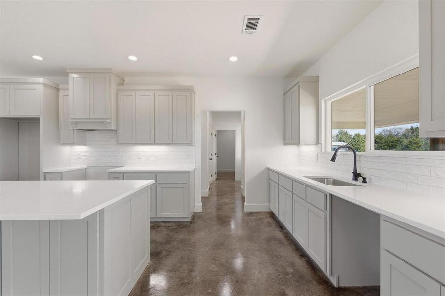 The kitchen features an island, white countertops, gray cabinetry, and a white subway tile backsplash