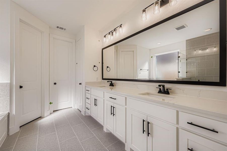 Bathroom featuring double vanity, light tile patterned flooring, and a tile shower