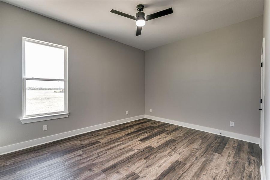 Empty room with ceiling fan and dark hardwood / wood-style floors