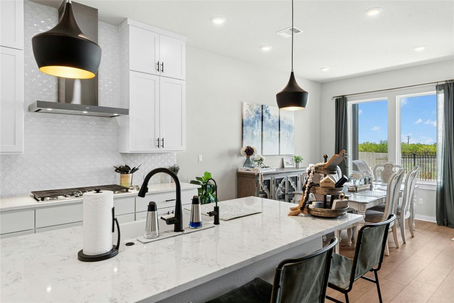 Kitchen featuring white cabinetry, backsplash, light stone counters, and light wood-style flooring