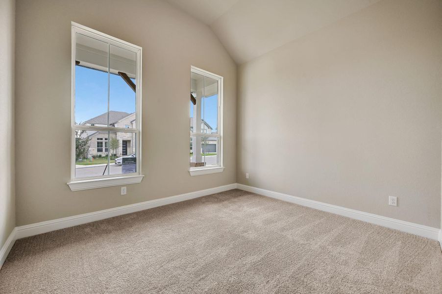 Empty room with lofted ceiling, plenty of natural light, and light colored carpet