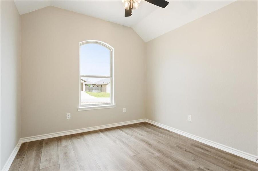 Unfurnished room featuring ceiling fan, lofted ceiling, and wood finished floors Unfurnished room featuring ceiling fan, lofted ceiling, and wood finished floors
