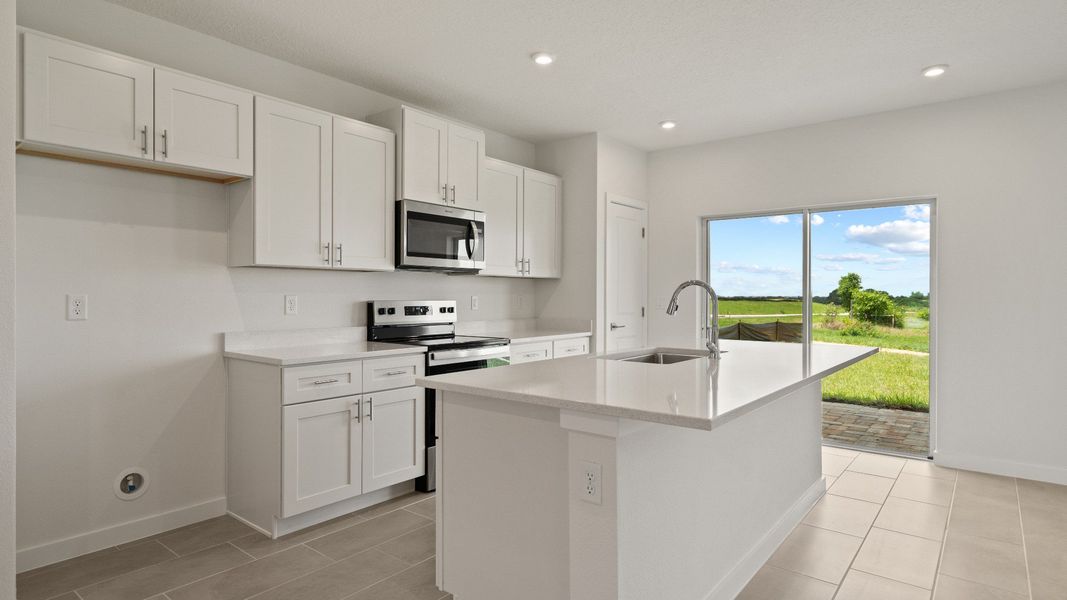 Bright kitchen with shaker-style cabinetry, large island, and natural light pouring in through sliding glass doors
