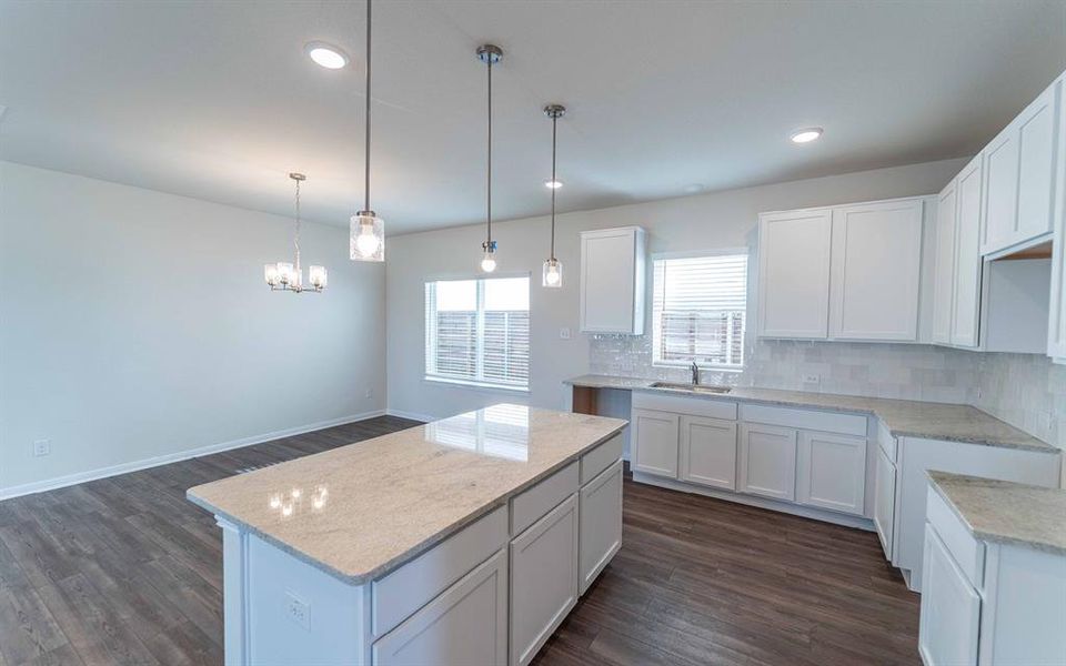Kitchen island with a light-toned countertop, white cabinetry, wood-finish flooring, recessed lighting, and pendant fixtures