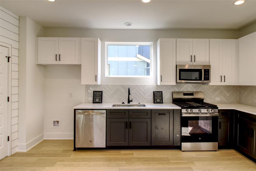 Kitchen featuring white cabinets, appliances with stainless steel finishes, light wood-style flooring, recessed lighting, and light stone countertops Kitchen featuring white cabinets, appliances with stainless steel finishes, light wood-style flooring, recessed lighting, and light stone countertops