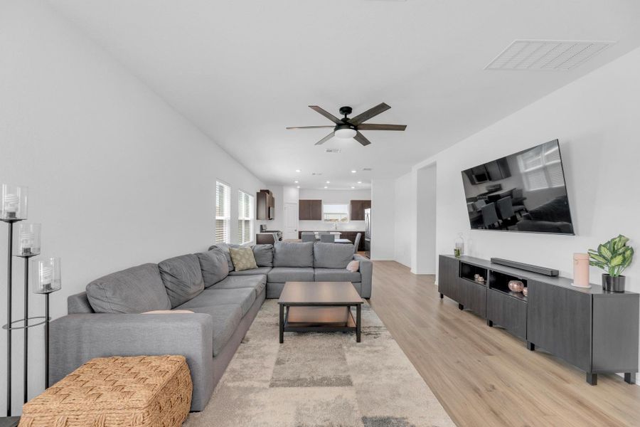 Living room with light wood-style floors, recessed lighting, visible vents, and ceiling fan