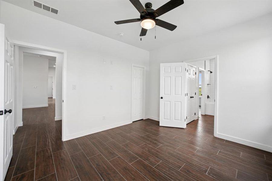 Unfurnished bedroom with wood tiled floors, ceiling fan, and ensuite bathroom