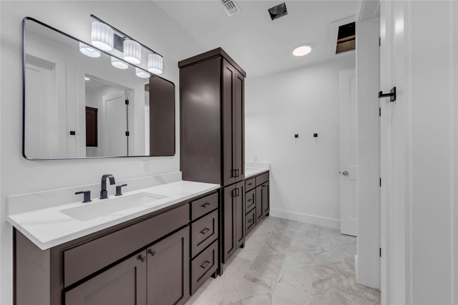 Gleaming stone countertops and custom dark wood cabinetry elevate this elegant bathroom space.