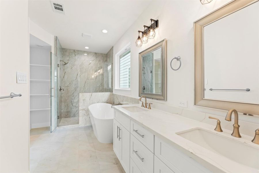 This bathroom features a sleek design with a double vanity, modern fixtures, a freestanding tub, and a glass-enclosed shower, offering a luxurious and spacious feel.