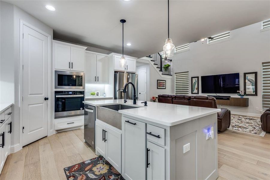 Kitchen featuring white cabinetry, open floor plan, and decorative light fixtures