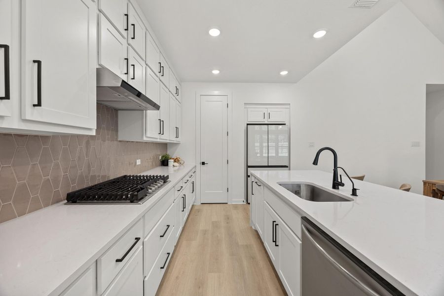 Kitchen featuring white cabinets, light wood-style floors, stainless steel appliances, light stone countertops, and recessed lighting