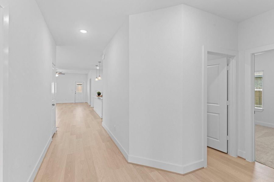 Step into this bright and open hallway that leads you through the heart of the home! The clean design, luxury vinyl plank flooring, and soft wall colors make the space feel warm and welcoming from the moment you enter.