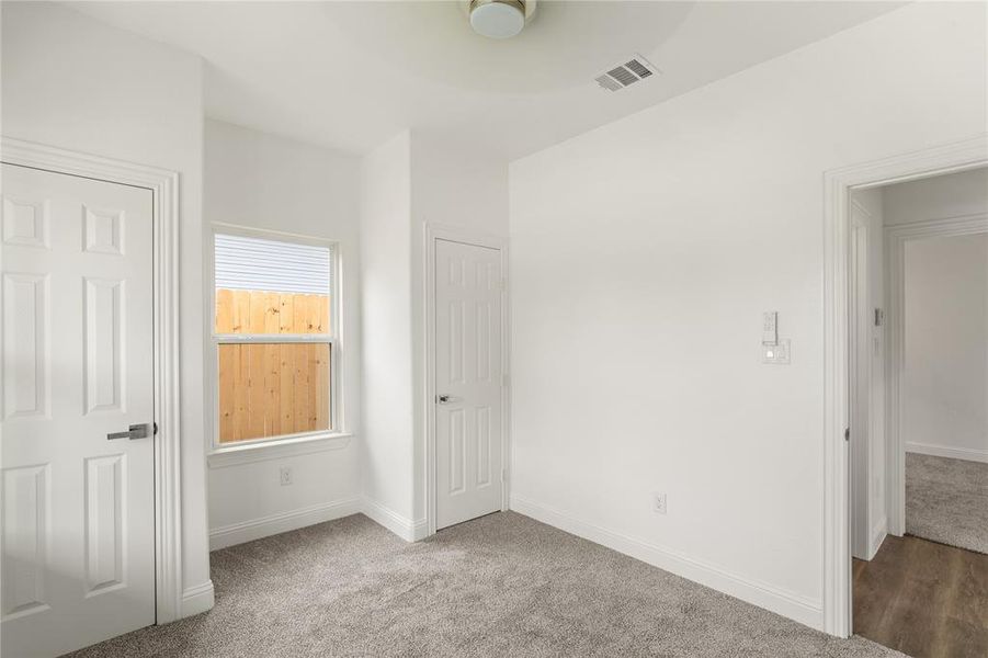 Neutral interior space with light gray carpet, white walls, and a single window featuring horizontal blinds