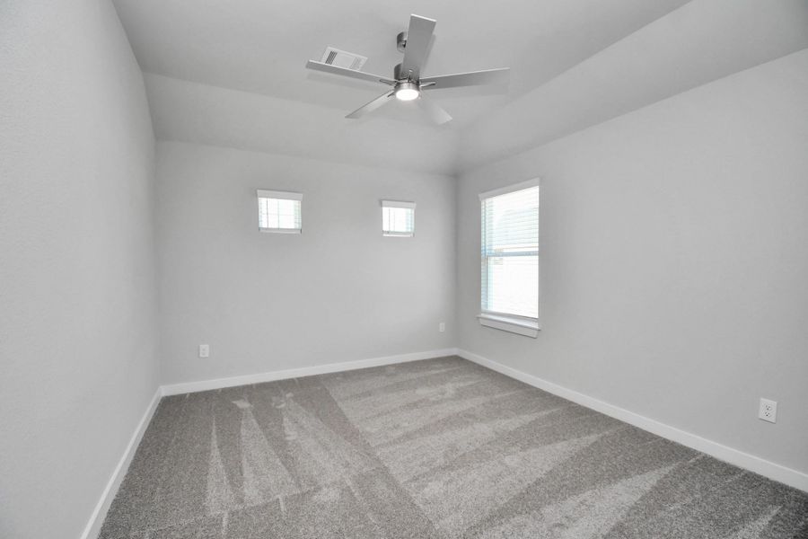 Secondary bedroom features plush carpeting, large windows that let in plenty of natural light, bright paint, and spacious closets. Sample photo of completed home with similar floor plan. Actual colors and selections may vary.