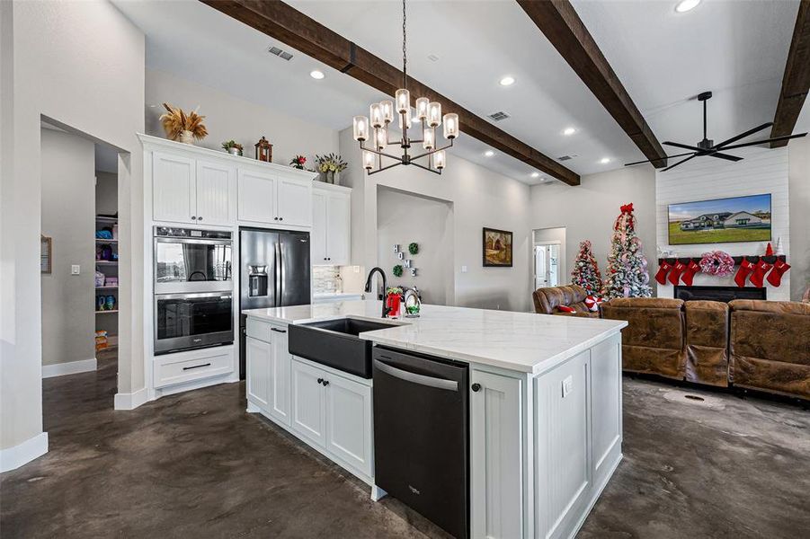 Kitchen with white cabinets, finished concrete flooring, stainless steel double oven, hanging light fixtures, and ceiling fan Kitchen with white cabinets, finished concrete flooring, stainless steel double oven, hanging light fixtures, and ceiling fan