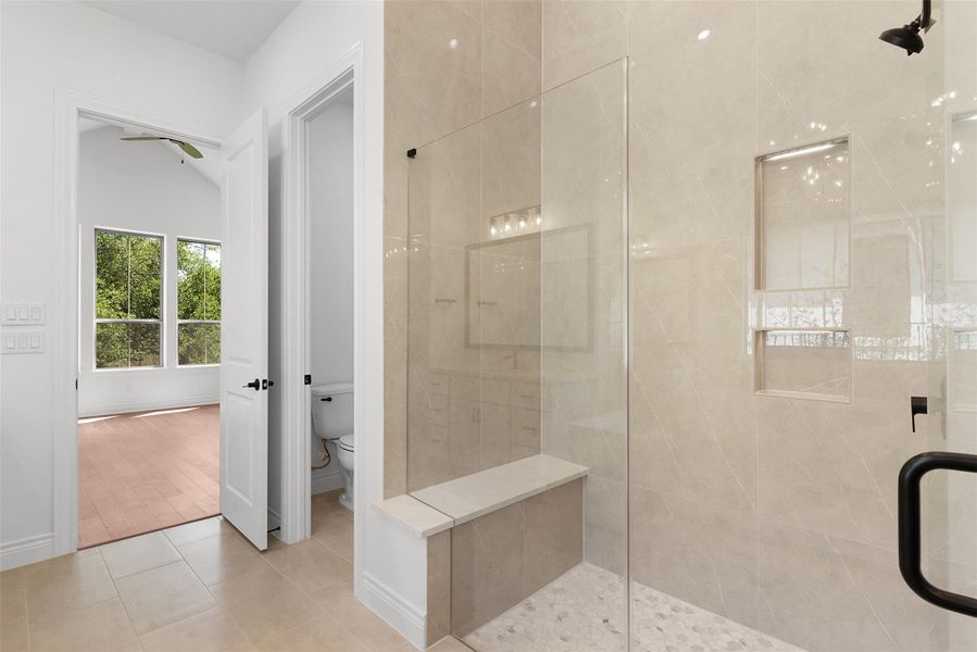 This bathroom features a spacious walk-in shower with a glass enclosure, a built-in bench, and a textured floor