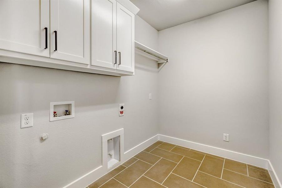 Laundry room with washer hookup, hookup for an electric dryer, cabinet space, light tile patterned floors, and gas dryer hookup