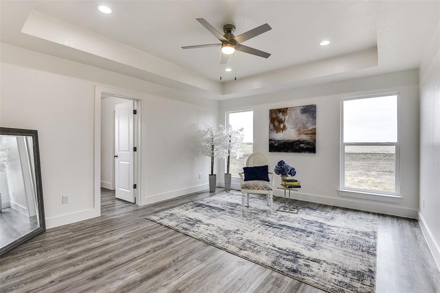 Sitting room featuring baseboards, a tray ceiling, and wood finished floors