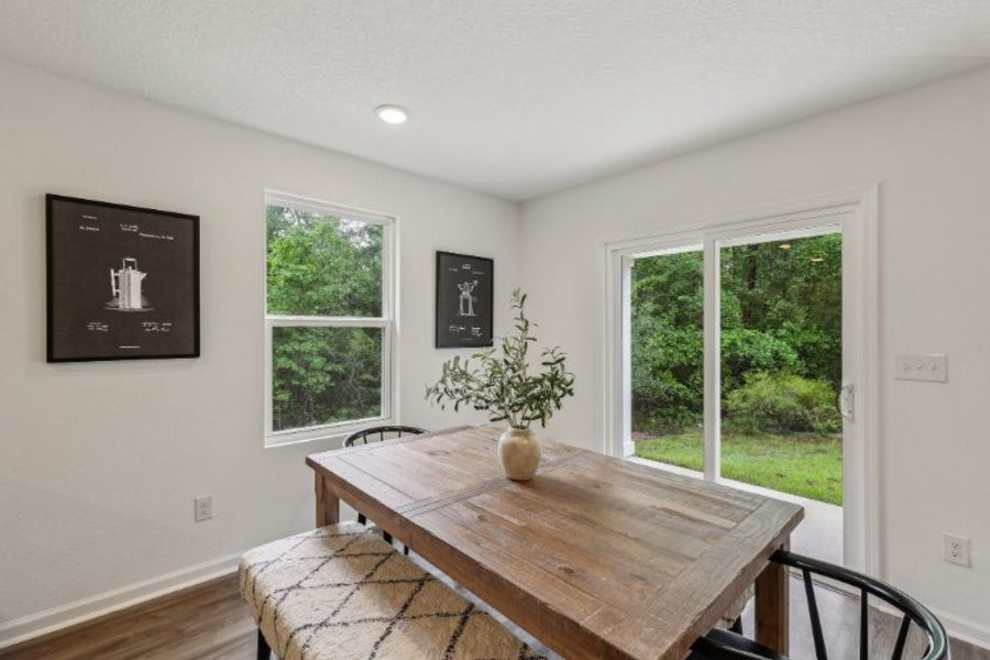 A table with a vase of flowers on it in a room with windows.