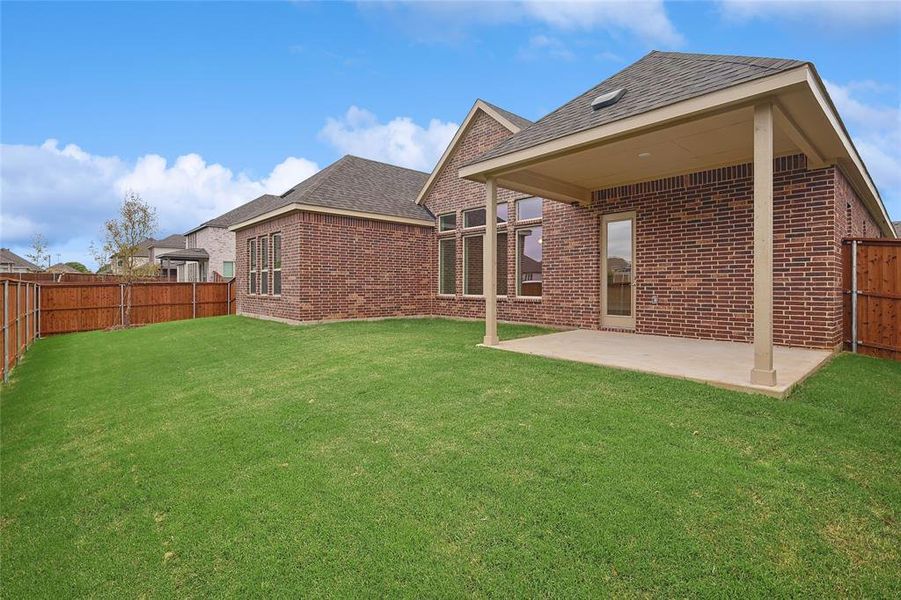 Rear view of property featuring a lawn and a patio area