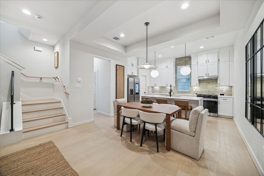 Dining area connects effortlessly to the kitchen, creating a comfortable setting for everyday meals or entertaining. Modern light fixtures and warm finishes balance style and function, while the open stairway enhances the sense of flow throughout the home.